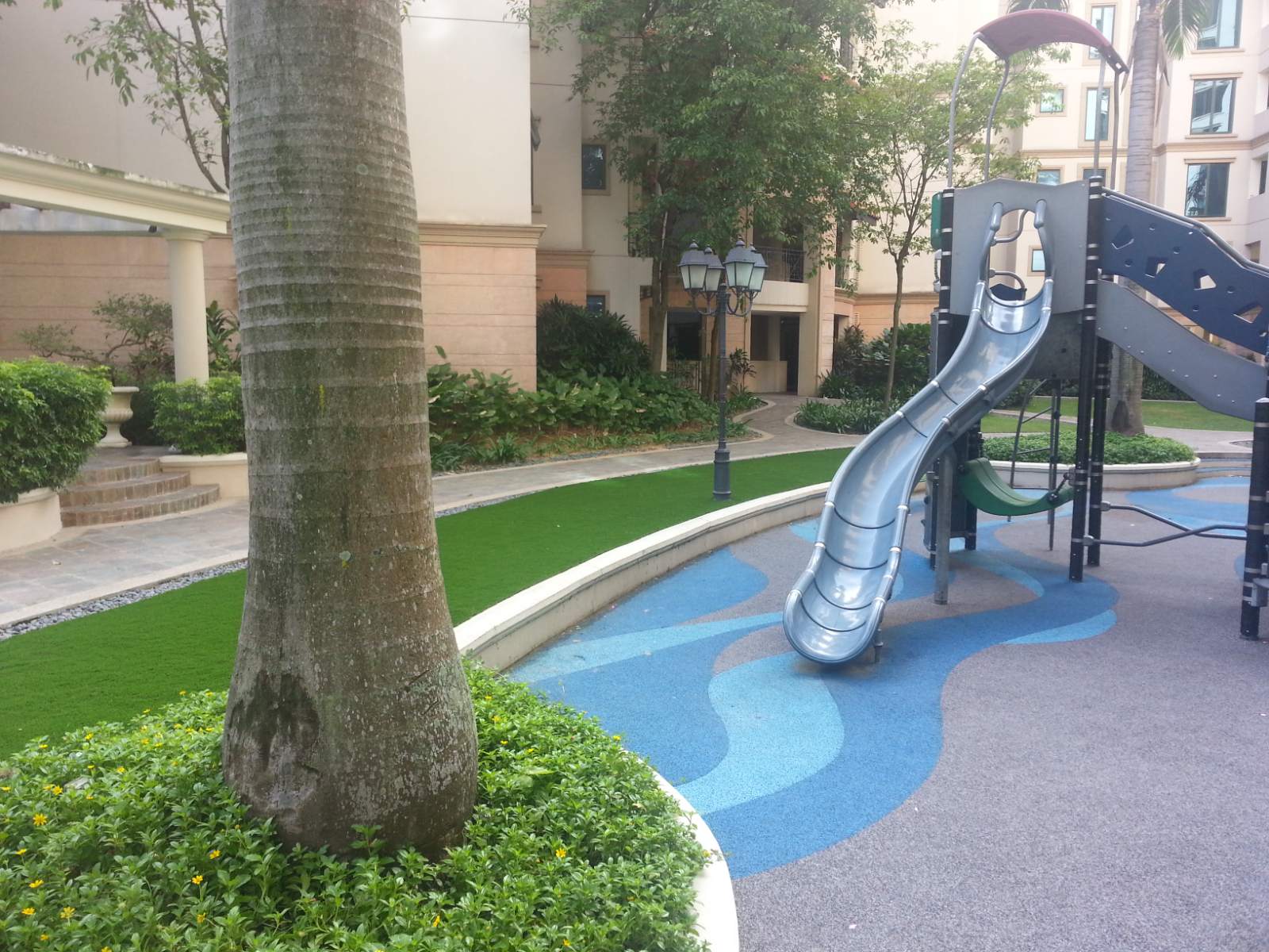Lush synthetic grass lawn around the playground at a Pebble Bay condominium
