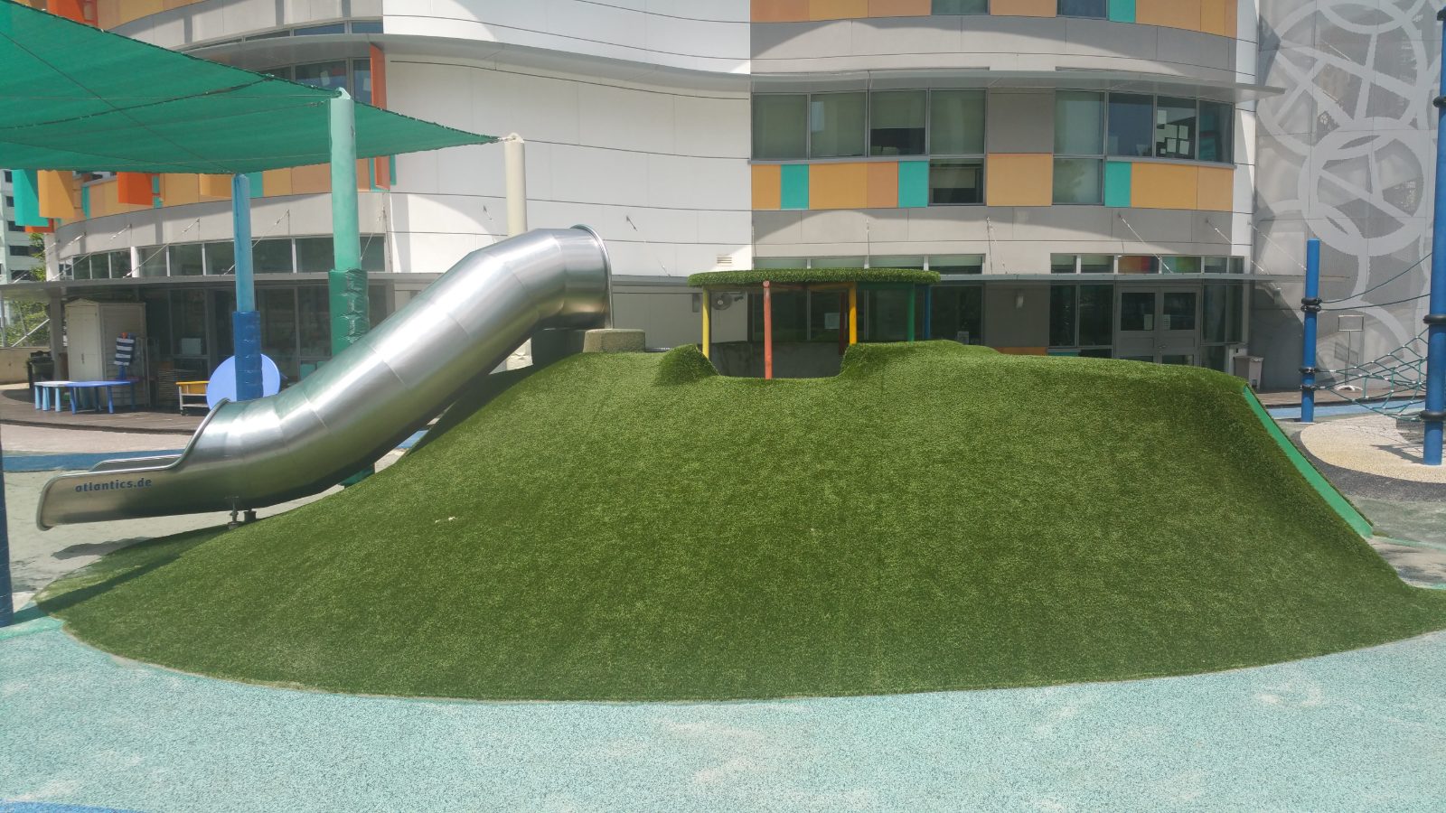 Synthetic grass play mound with a tube slide at United World College